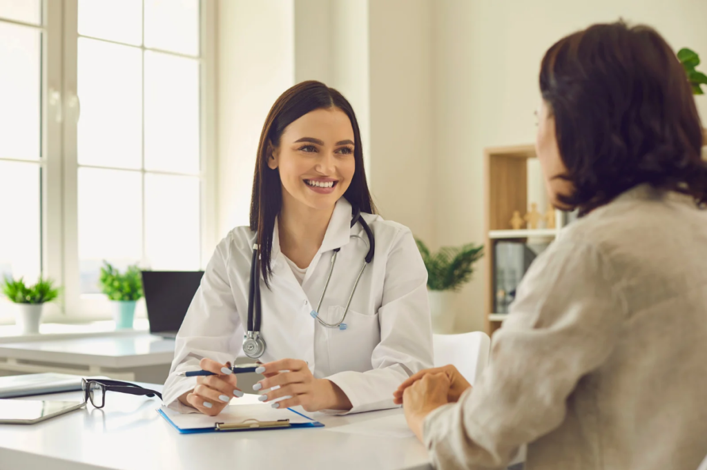 Lächelnde Ärztin im Gespräch mit einer Patientin in einer Praxis.